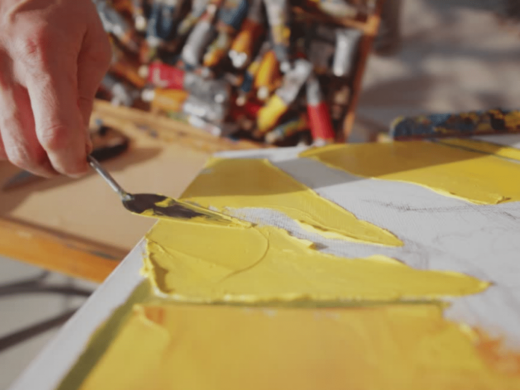 Artist creating handmade textured oil painting with palette knife.